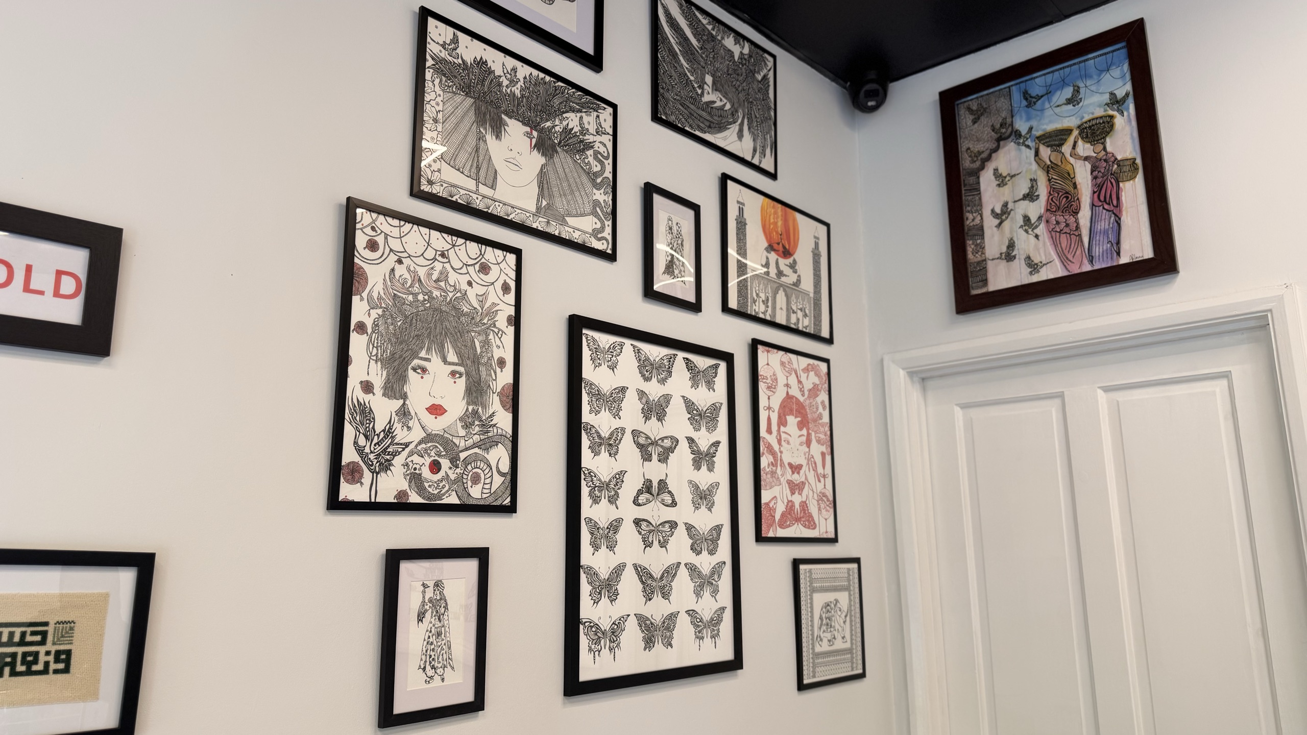 A corner of the café's gallery wall, hung with framed drawings and prints by local artists