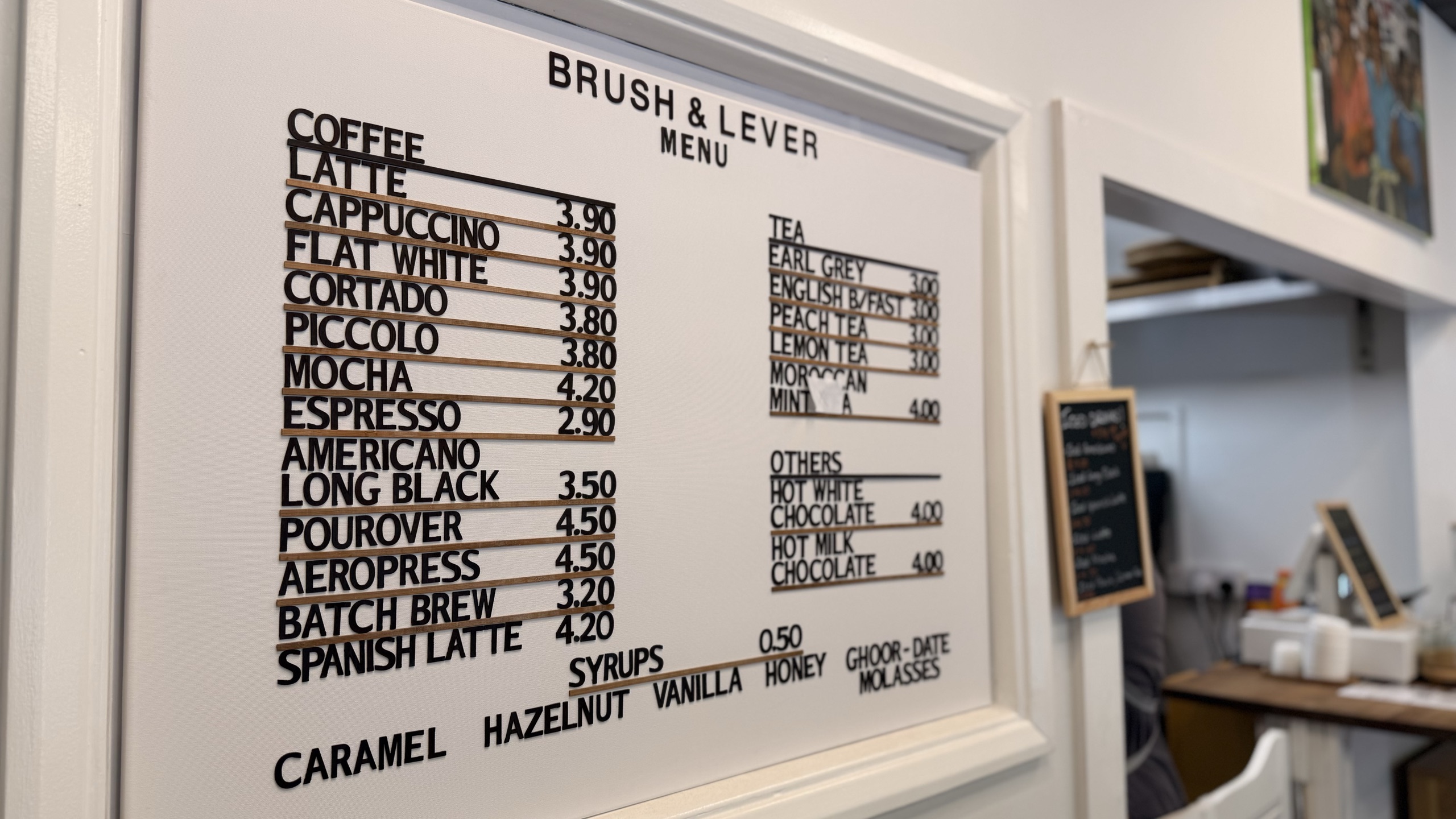 The Brush & Lever menu board — coffee, tea and syrups